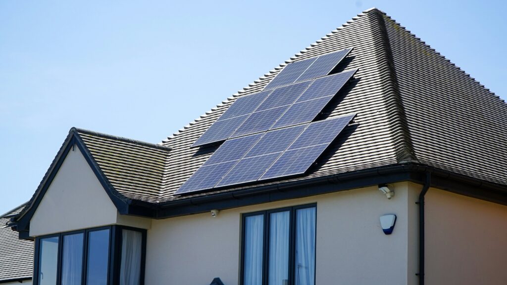 Solpaneler installerade på ett sluttande hustak med blå himmel i bakgrunden, vilket visar ett energieffektivt hem med fokus på hållbarhet.